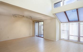 an empty living room with a sliding glass door and a balcony